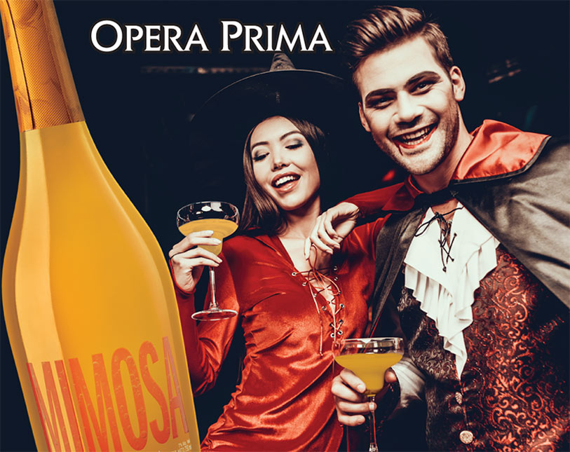 A woman in a witch costume and a man in a vampire costume smile while holding glasses of mimosa. A large bottle labeled Mimosa is in the foreground with Opera Prima written above them.