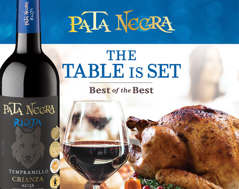 A bottle of Pata Negra Rioja wine and a glass of red wine sit next to a roasted turkey, with the text Pata Negra. The Table is Set. Best of the Best in the background.